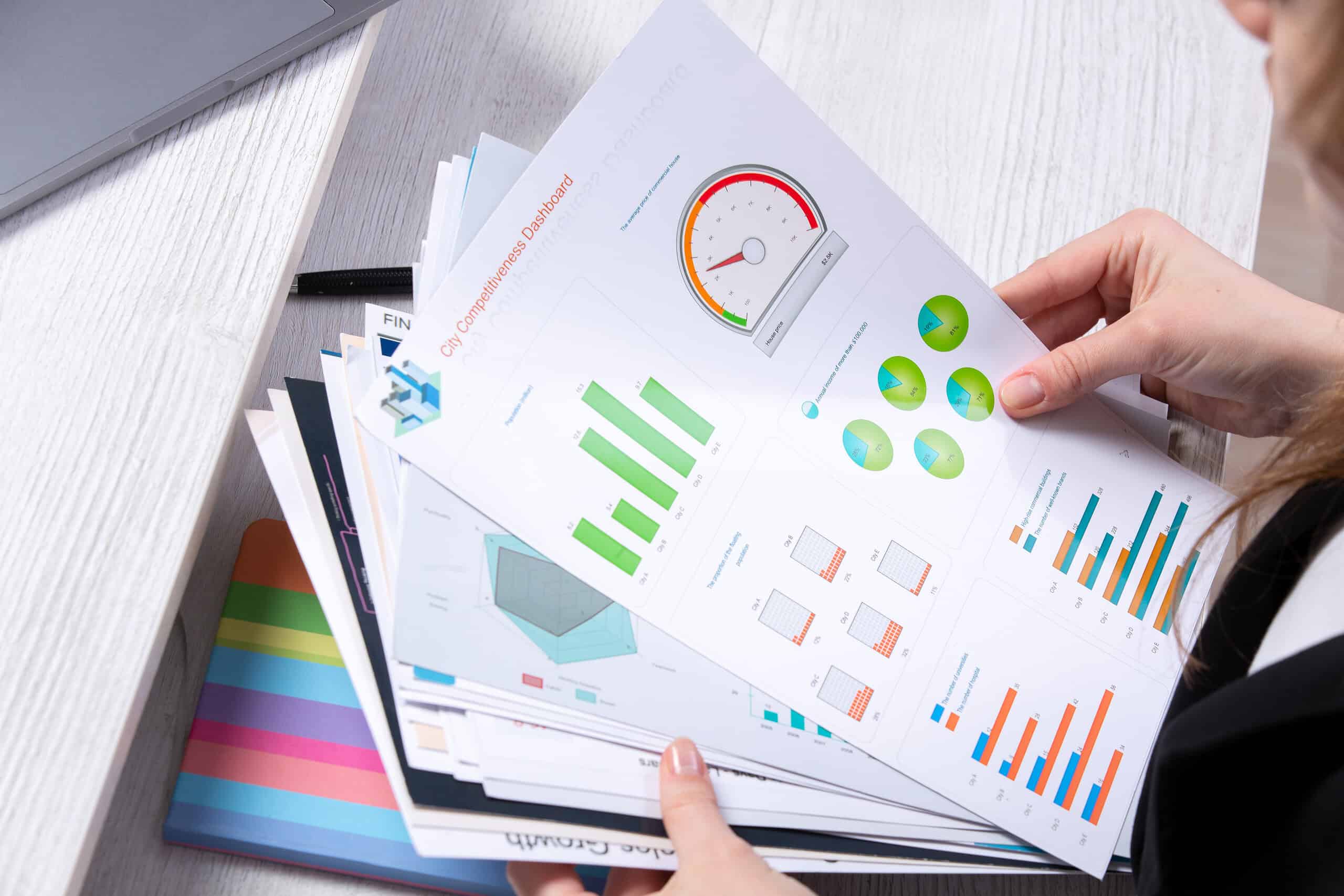 Close-up of a professional holding a printed Competitor Analysis Albania report featuring performance graphs and keyword data charts.